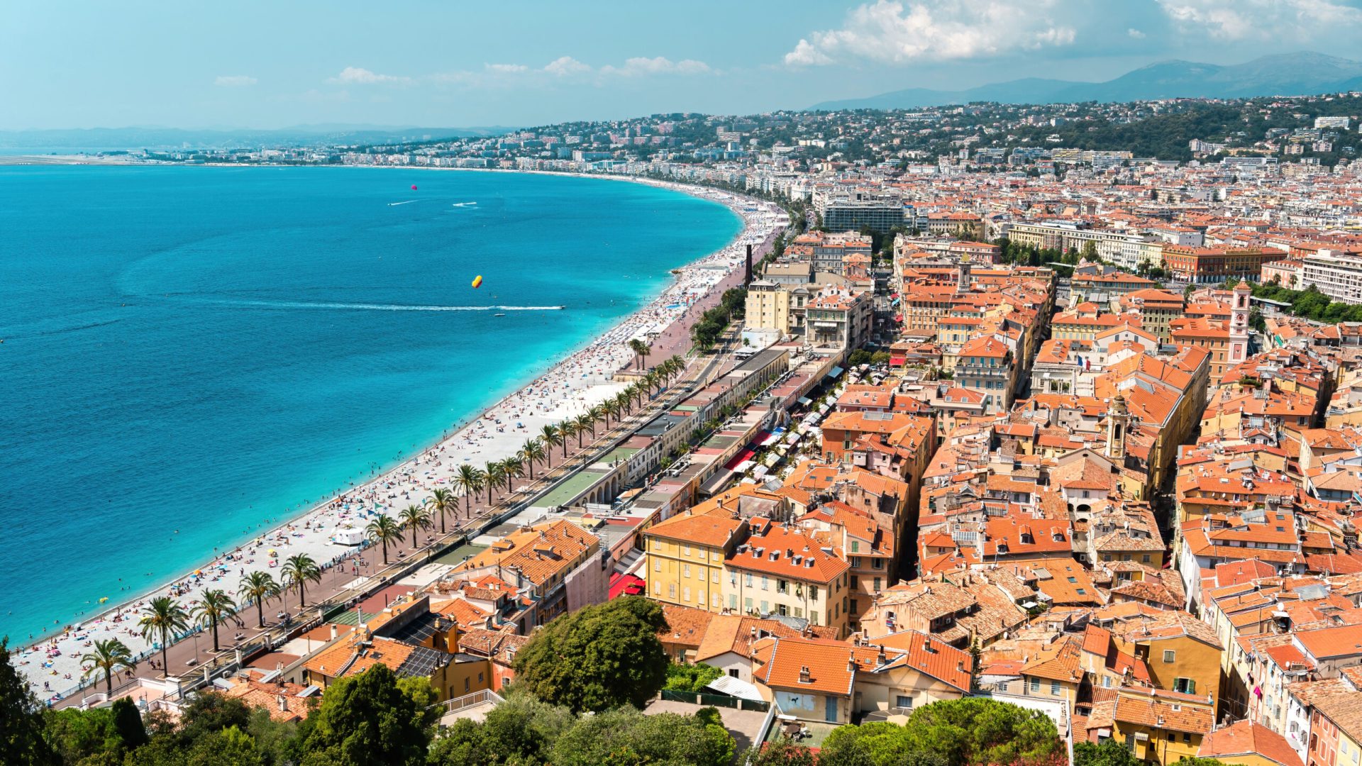 View of the cote d’Azur in Nice, France View of the cote d'Azur in Nice, France. Multiple resting on the beach people, buildings, blue water of the Mediterranean sea, hills on the background
